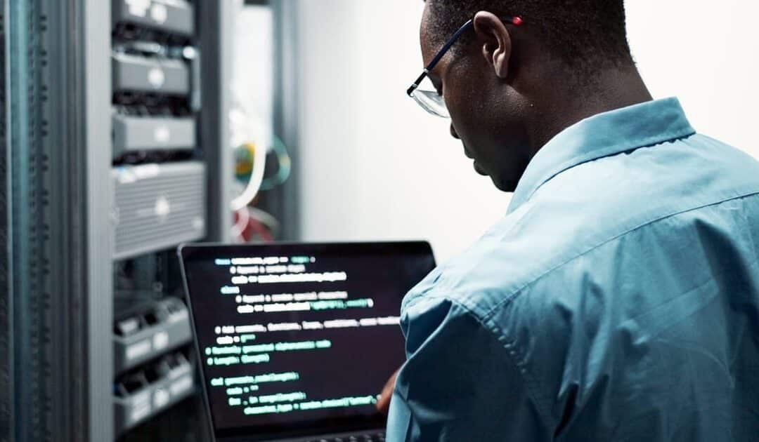 office man standing in the server room with a device in his hands